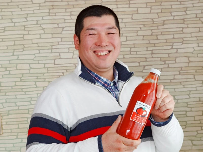 トマトジュースを手にする原崎農園の原崎さん