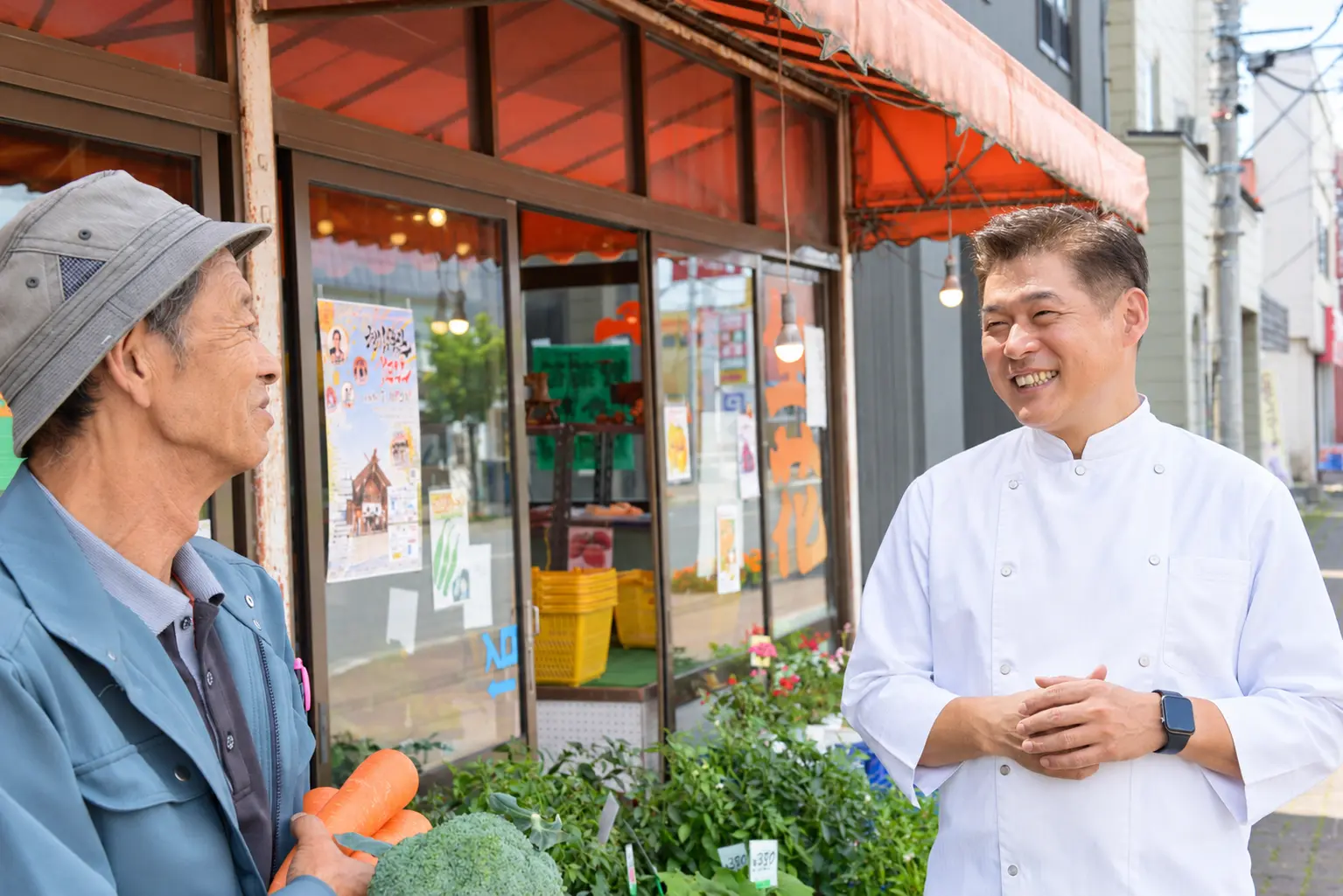 入江商店の店頭で野菜を手にエスペリオ代表・矢野竜二郎と話す入江さん