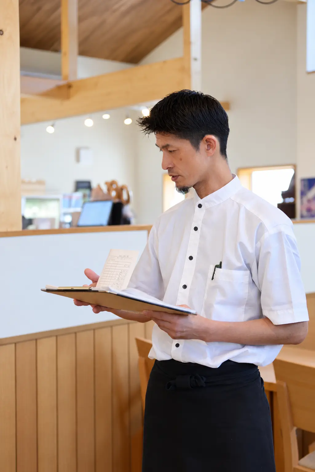 客席を見ながら仕事をするレストラン店長 H.I.