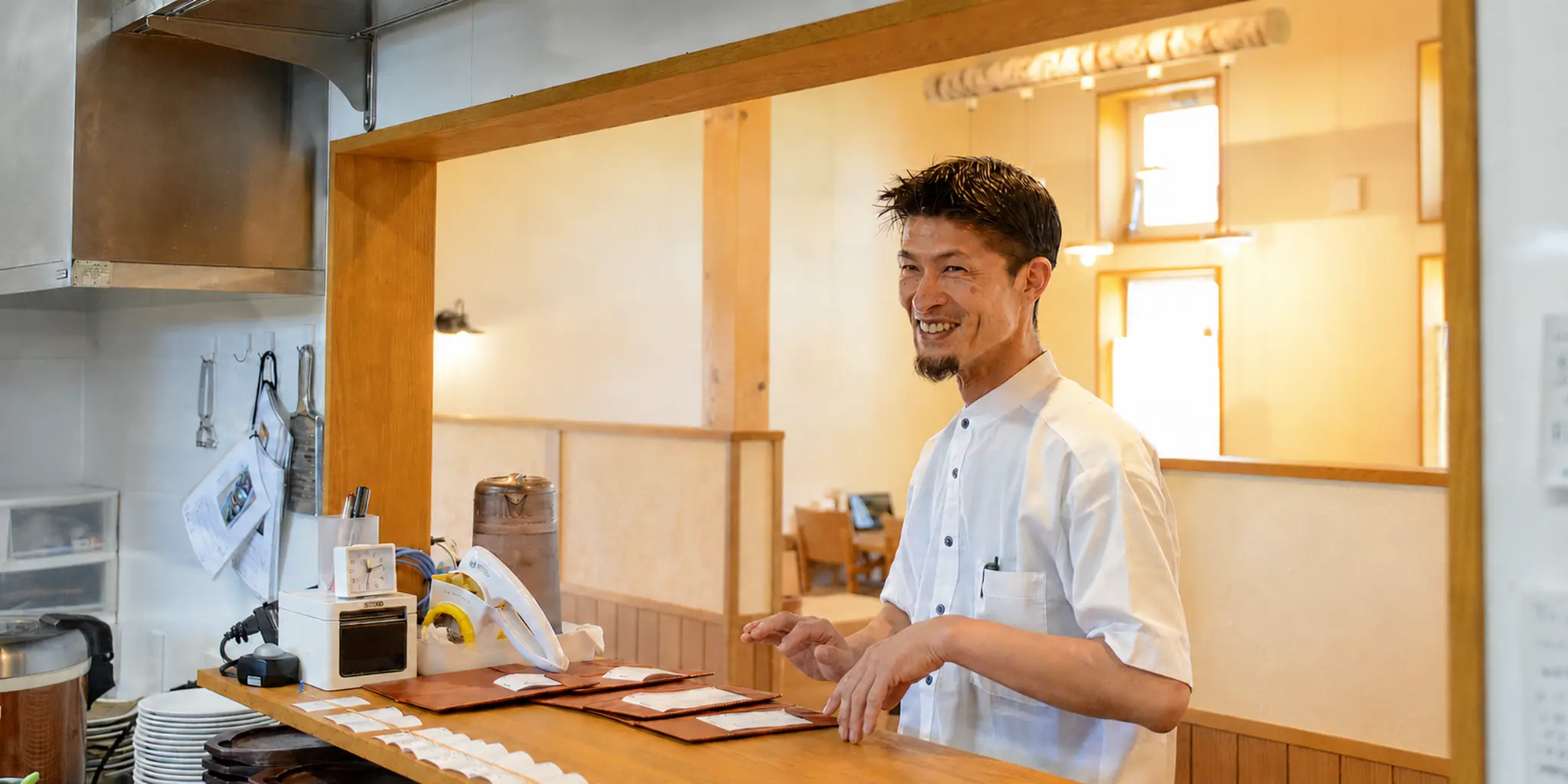 レストランの厨房で笑顔を見せる店長 H.I.