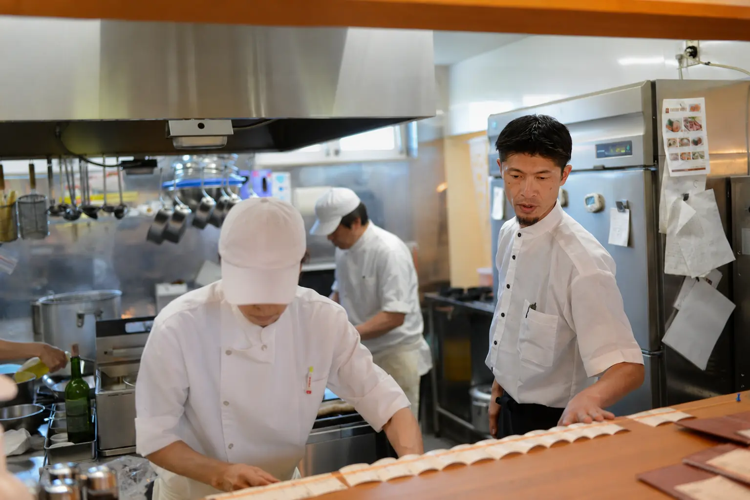 厨房でスタッフの仕事を見守るレストラン店長 H.I.